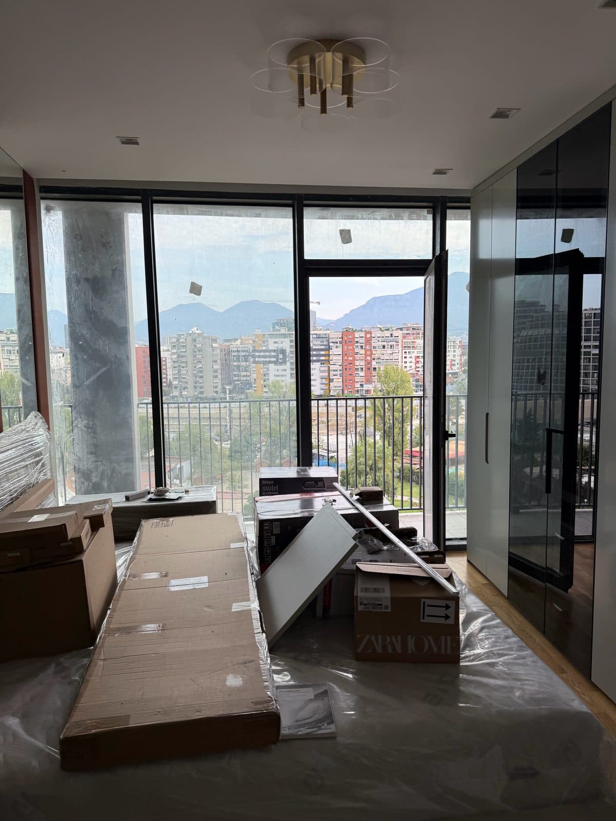 Apartament i ri pas punimeve, me najlon në dysheme, kuti dhe ngjitëse mbi xhama, para pastrimit